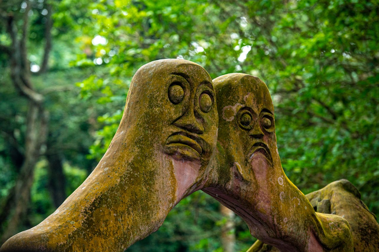 Two ancient carved stone statues in the lush Osun forest in Nigeria.